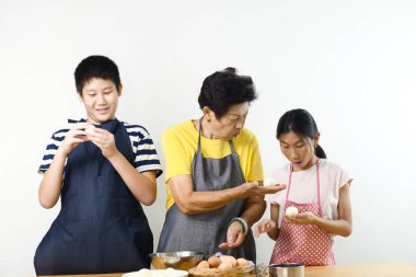 Asyalı son sınıf öğrencisi torunlarına yumurta soymayı öğretiyor. Yaşam tarzı konsepti..