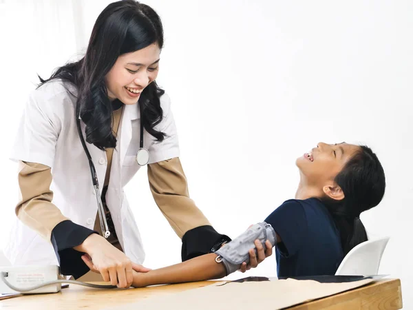 Asian female doctor in a white coat measures pressure on a child. nurse doing a checkup at clinic.