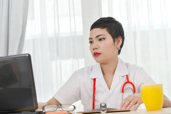 Female Asian doctor working at office desk