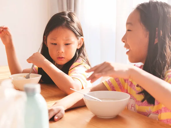 かわいいアジアの女の子は一緒に朝食のためにご飯スープを食べる家の窓の近く — ストック写真