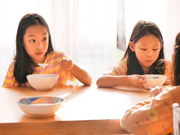 かわいいアジアの女の子は一緒に朝食のためにご飯スープを食べる家の窓の近く — ストック写真