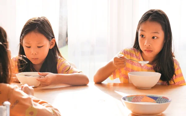 かわいいアジアの女の子は一緒に朝食のためにご飯スープを食べる家の窓の近く — ストック写真