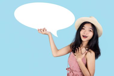 Gülümseyen Asyalı turist mavi arka planda beyaz konuşma balonu tutuyor.