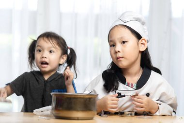 Mutlu Asyalı kızlar, evde aşçılık oynuyorlar..