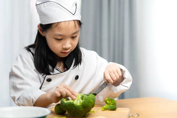 Šťastná Asijské Dívka Kuchař Uniforma Chopping Brokolice Doma — Stock fotografie