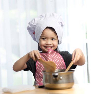 Asyalı çocuk evde aşçıyı oynuyor, evde konsept yapıyor, hareket bulanıklığı yaşıyor..