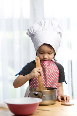 Asyalı çocuk evde aşçıyı oynuyor, evde kalıp konsept yapıyor..