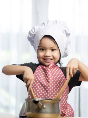 Asyalı çocuk evde aşçıyı oynuyor, evde kalıp konsept yapıyor..