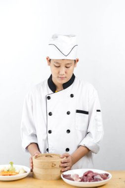 Genç Asyalı şef elinde hamur tatlısı tutuyor..