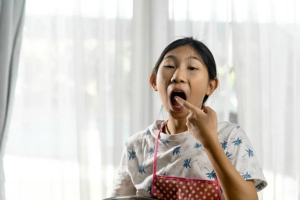 Glad Asiatisk Flicka Slickar Choklad Medan Gör Hemmagjord Svamp Kaka — Stockfoto
