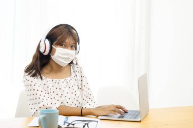 İnternette ve karantinada dizüstü bilgisayar kullanan Asyalı genç kız..