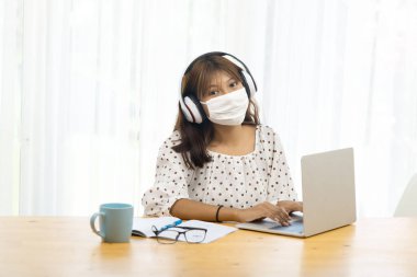 İnternette ve karantinada dizüstü bilgisayar kullanan Asyalı genç kız..