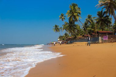 palmiye ağaçları ve bir ev ile Goa sahilinde bir adam