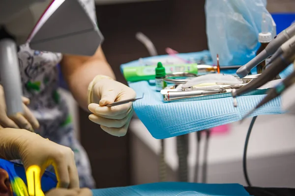Dentist\'s hands in rubber gloves in the process of treatment and prosthetics. Doctor\'s hand with dental instrument.
