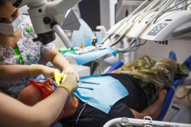 Tedavi ve protez sürecinde lastik eldivenlerin içindeki dişçi elleri. Diş aletleriyle doktor eli..