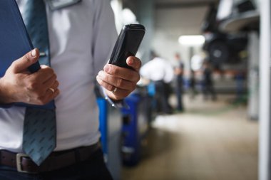 Kayıt için bir tablet ile beyaz bir gömlek ile servis istasyonunda müfettiş ustasının eli. Serviste onarım için araçların kaydı, iş süreci.