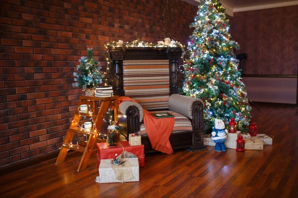 Decorated for The new year Interior of the house. Christmas tree and decorated Studio, garlands of lights, decorations, gift boxes in a cozy home, a large armchair and a fireplace.