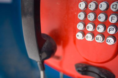 Eski kırmızı düğmeli bir ankesörlü telefon. Telefonunda numaralar ve semboller olan yuvarlak düğmeler.