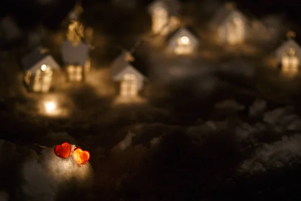 Two Red Glass Hearts Snow Front Garland Wooden Houses Light — Stock Photo, Image