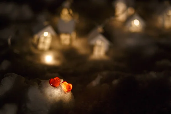 Dos Corazones Cristal Rojo Nieve Frente Una Guirnalda Casas Madera — Foto de Stock