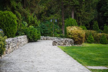Tiled road in the Park. Grey tiles, steps, green Park in Bulgaria