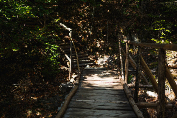 Wooden bridge with steps on the eco-trail along the rocks and mountain river in Bulgaria, Smolyan city. Equipped tourist road through the forest for sightseeing tours and walks