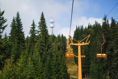 Yaz mevsiminde Bulgaristan 'ın kayak alanında teleferik. Sarı iskemle kayak asansörü, Rodop dağlarındaki yeşil köknar ve çam ağaçları arasındadır.