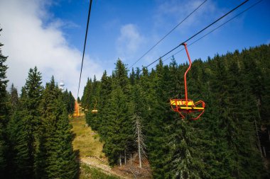 Yaz mevsiminde Bulgaristan 'ın kayak alanında teleferik. Sarı iskemle kayak asansörü, Rodop dağlarındaki yeşil köknar ve çam ağaçları arasındadır.
