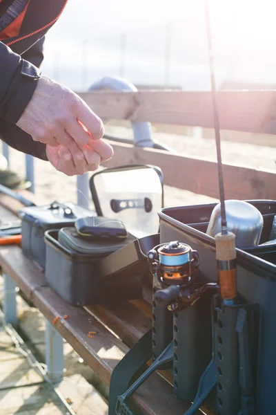 Fishing rod in the hands of a fisherman on the lake. Fisherman\'s hands with spinning on the background of water