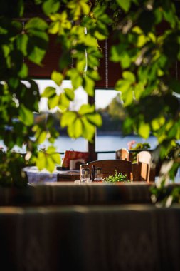 Pencere taze çiçekler ve deniz manzaralı yeşillik ve sandalyeli bir balkonla süslenmiş. Bulgaristan 'da deniz kıyısında bir restoranın içi rahattır.