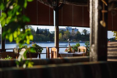 Pencere taze çiçekler ve deniz manzaralı yeşillik ve sandalyeli bir balkonla süslenmiş. Bulgaristan 'da deniz kıyısında bir restoranın içi rahattır.