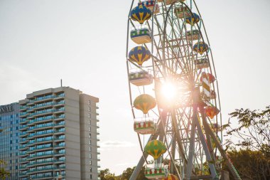 Güneşin parlak ışığında balon şeklinde kabinleri olan dönme dolap. Bulgaristan 'ın toprak seti üzerindeki parkta çocuklara ve yetişkinlere ilgi.