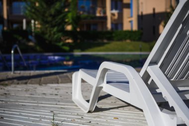 Havuzun yanında beyaz plastik güneş yatakları. Havuzun yanındaki otel dinlenme tesisi.