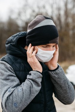 Korunaklı tıbbi maskeli bir adam. Karantina koşullarında koronovirüse karşı modern önlemler. Sıradan tarzda genç bir adam boş bir yolda yürüyor.