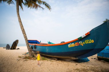 Hindistan, Kerala, Mararikulam-1 Şubat 2019. Kerala 'nın kumlu sahillerinde balıkçı tekneleri, Mararikulam balıkçı köyü. Palmiye ağaçlarının arasında parlak renkli bir tekne