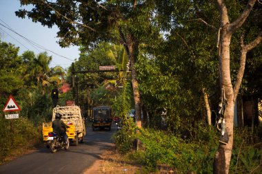 Hindistan, Kerala-3 Şubat 2019. Tipik bir Hint köyü yolu. Tropikal yeşillikler ve parlak güneş altında palmiye ağaçları arasında oto çekiş, kamyon ve motosiklet