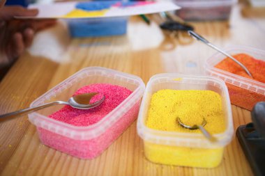 Evde, masada oturan çocuklar için yaratıcı eşyalar ve el sanatları. Boyalar ve fırçalar, makas, iplik ve kumaş kırıntıları - arka planda çocuğun ve ebeveynin elleri.