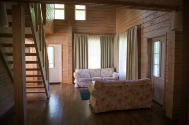 Golitsyno, Kaluga, Rusya-18 Mayıs 2019. Kır evinde, oturma odasının içi ahşap. Aile tatilleri için kırsal bir evde, parlak bir oturma odasında merdivenler ve bir kanepe.