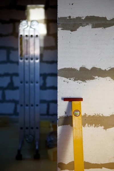 The yellow building level is leaning against the wall of a building under construction made of aerated concrete blocks. Foam block walls, tools for leveling and construction. Background — Stock Image Yellow Building Level Leaning Wall Building Construction Made Aerated Concrete Stock Picture