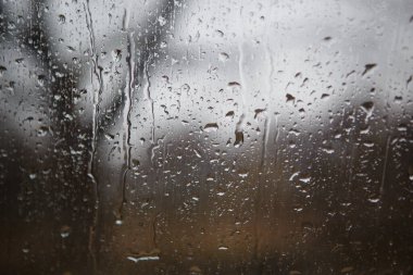 Araba penceresi yağmur damlalarıyla ıslanmış. Yağmurda yol ve yan aynaların ön cam manzarasından. Arkaplan