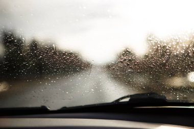 Araba penceresi yağmur damlalarıyla ıslanmış. Yağmurda yol ve yan aynaların ön cam manzarasından. Arkaplan
