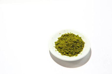 Japon kibrit çayının yeşil tozu, beyaz arka planda izole bir tabakta. Gevşek toz