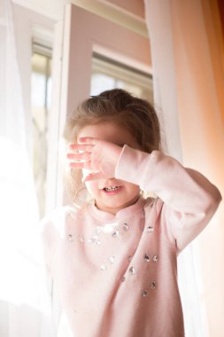 Sarışın saçlı küçük kız eli yorgunluktan dolayı yüzünü kapadı. Çocukların duyguları, yakın plan.