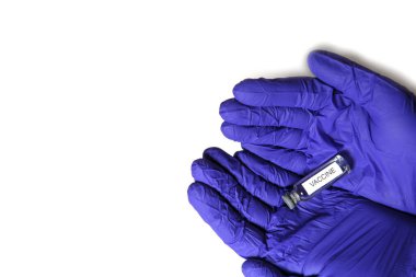 Doktorun elleri mavi tıbbi lastik eldivenlerde üzerinde VACCINE yazan bir şişe tutuyor. Tıbbi konsept, salgının tedavisini içeren şişe. Beyaz arkaplan