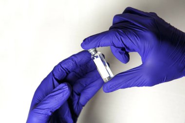 Doktorun elleri mavi tıbbi kauçuk eldivenler içinde mesaj için yer olan bir şişe tutuyor. Tıbbi konsept, salgının tedavisini içeren şişe. Beyaz arkaplan