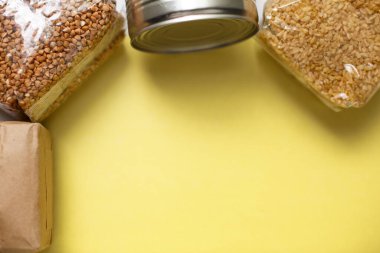 Gıda, sarı arka planda karantina süresi için gıda stoku sağlıyor. Pirinç, makarna, karabuğday, bulguru, konserve yiyecek. Yemek teslimatı, bağış, koronavirüs karantinası. Kopyalama alanı.