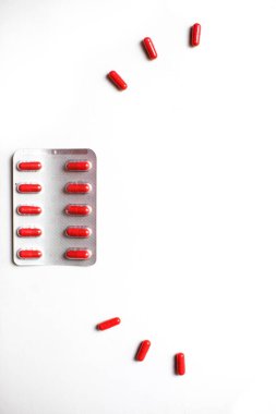 Beyaz arka planda kırmızı ilaçlar. Kapsüllerde tabletler, paketlerde haplar. İlaç, parlak vitaminler ve çocuklar için ilaçlar..