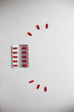 Beyaz arka planda kırmızı ilaçlar. Kapsüllerde tabletler, paketlerde haplar. İlaç, parlak vitaminler ve çocuklar için ilaçlar..