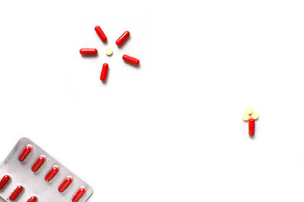 Red medicines on a white background - tablets in capsules, pills in packages. Pharmaceuticals, bright vitamins and medicines for children.