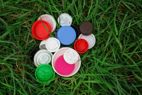 Colorful plastic bottle caps on the green grass. Volunteer charity event \